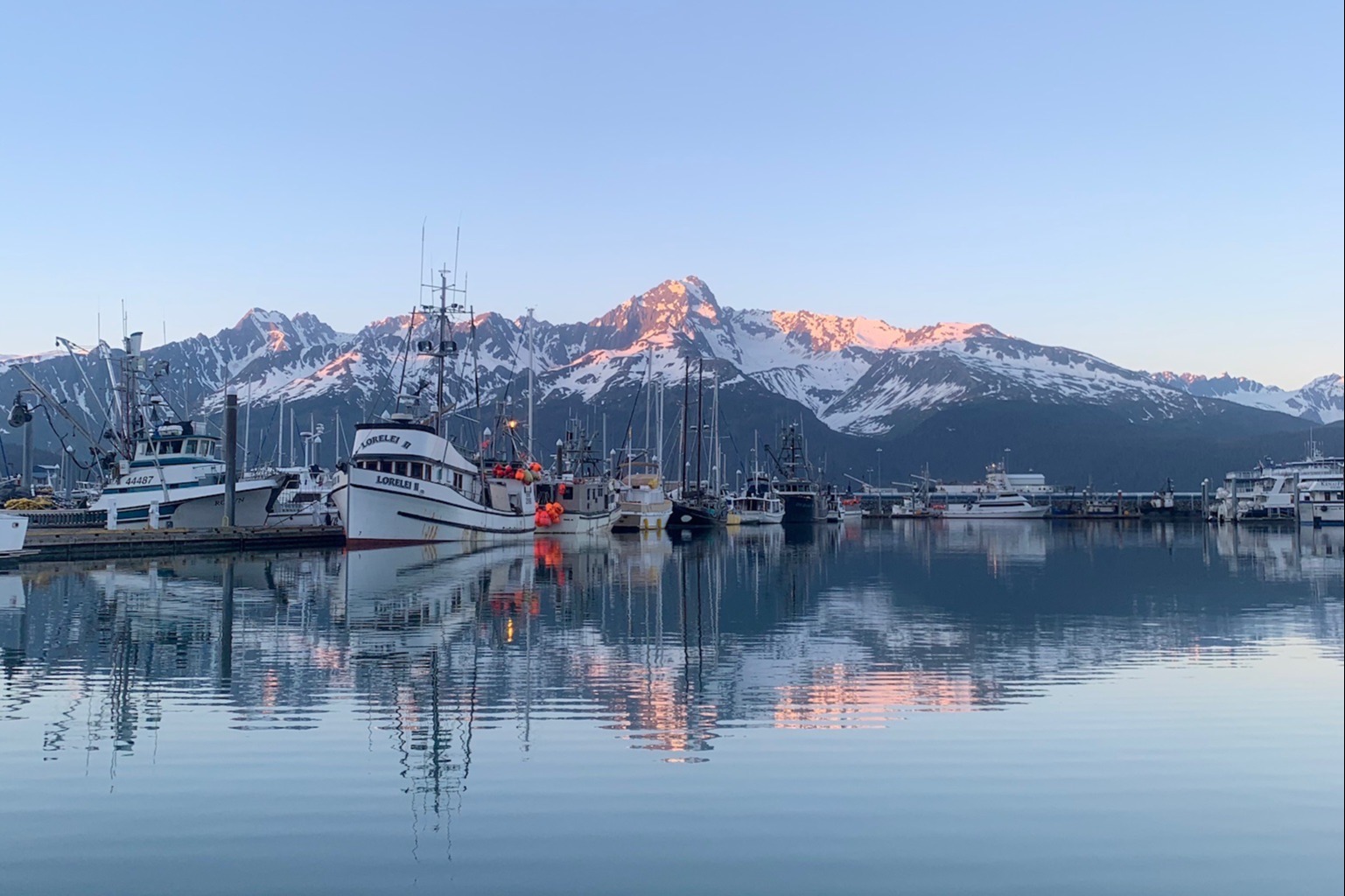 boats on a calm lake near snowy mountain peaks