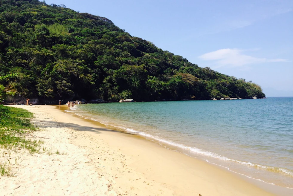 White sand with beach and green mountains at the back.