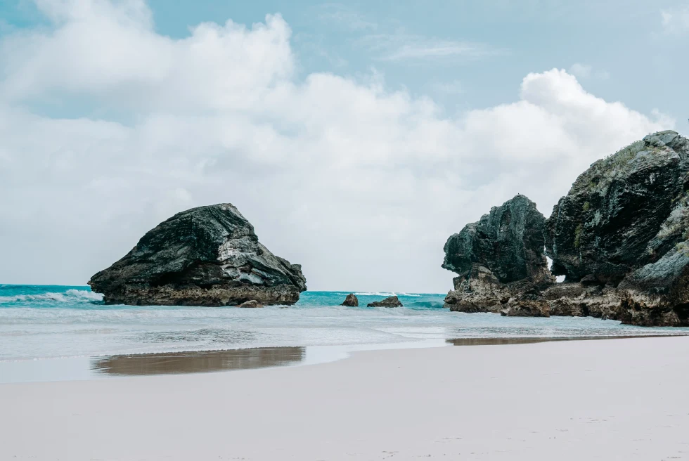 Large rocks on the beach next to body of water during daytime