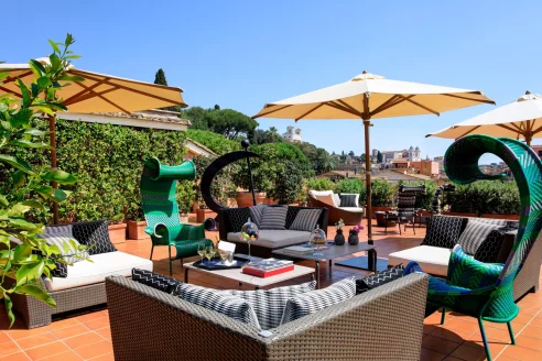 luxe, funky terrace in Rome with curly green chairs and umbrellas