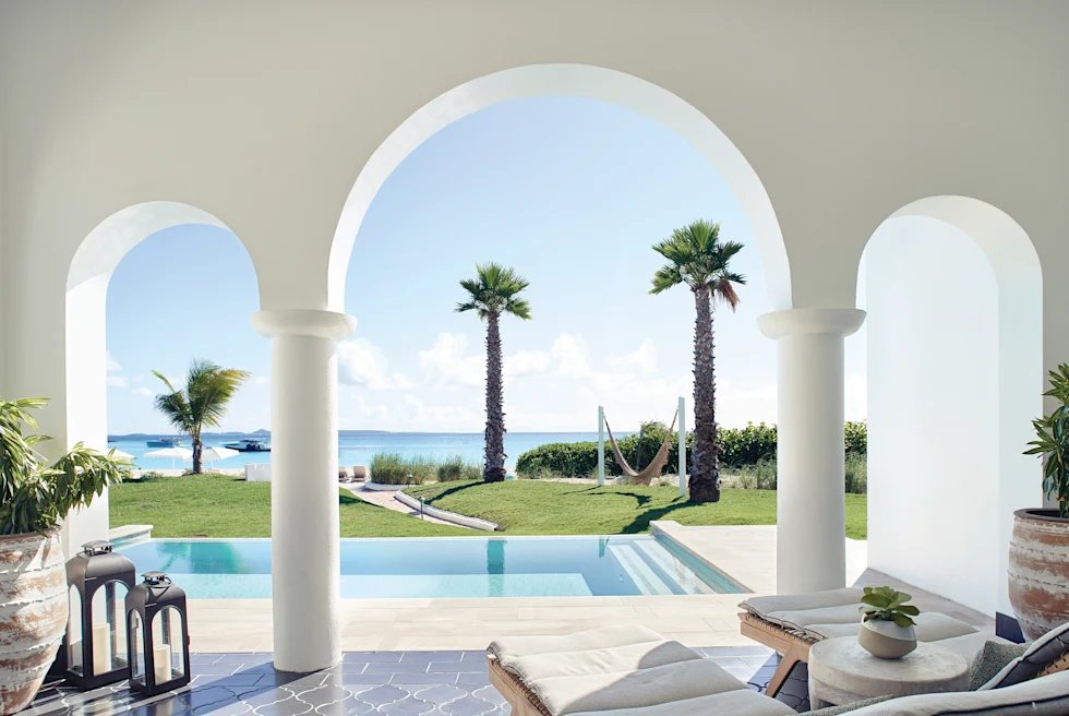 lounge chairs next to pool and palm trees overlooking the ocean