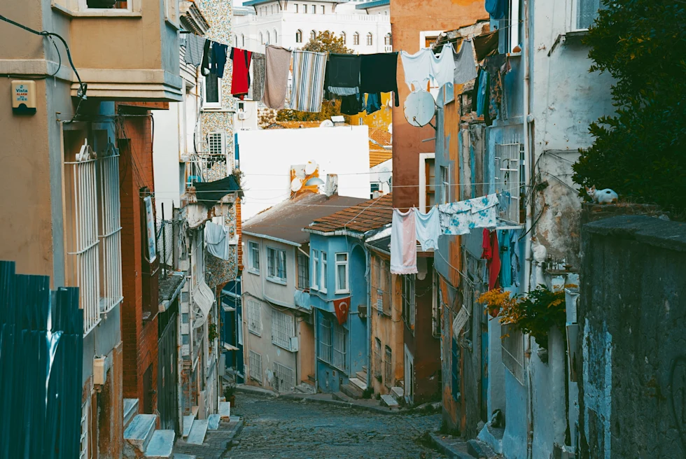 Cobblestone streets in Istanbul with laundry clothes lines lined with blue orange and white buildings with windows