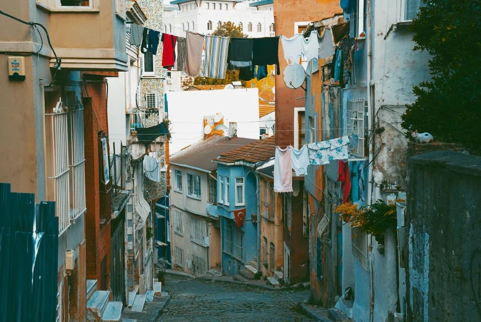 Cobblestone streets in Istanbul with laundry clothes lines lined with blue orange and white buildings with windows