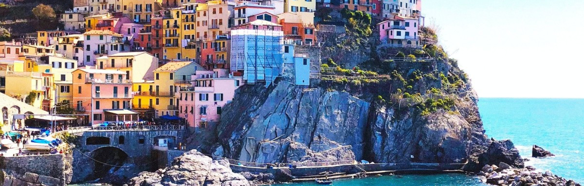 Colorful buildings of Cinque Terre on a cliff over the ocean on a sunny day. 