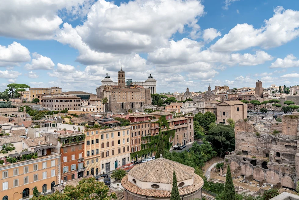 view of an old city a top a hill with blue sky and clouds