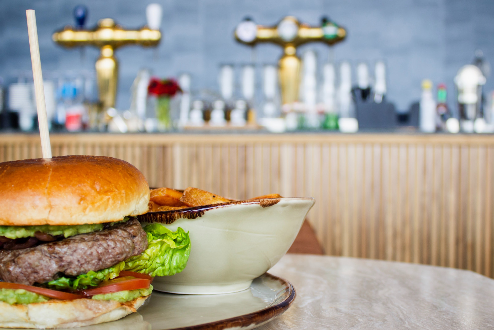 burger on plate with beer taps in the background