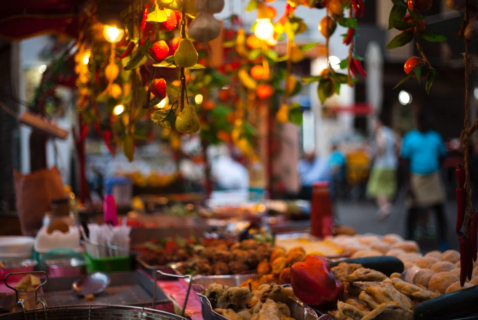 Lights hanging over a table of assorted fish and dishes with people in the background