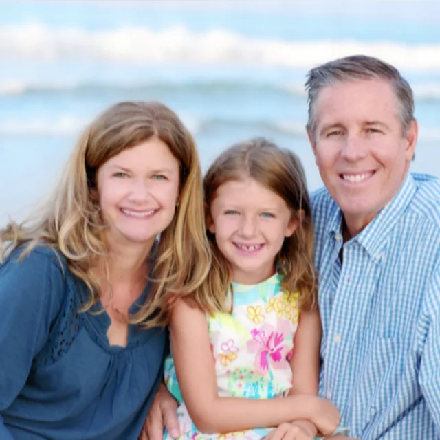 Travel Advisor Lisa Babic with her husband and daughter in front of a beach.