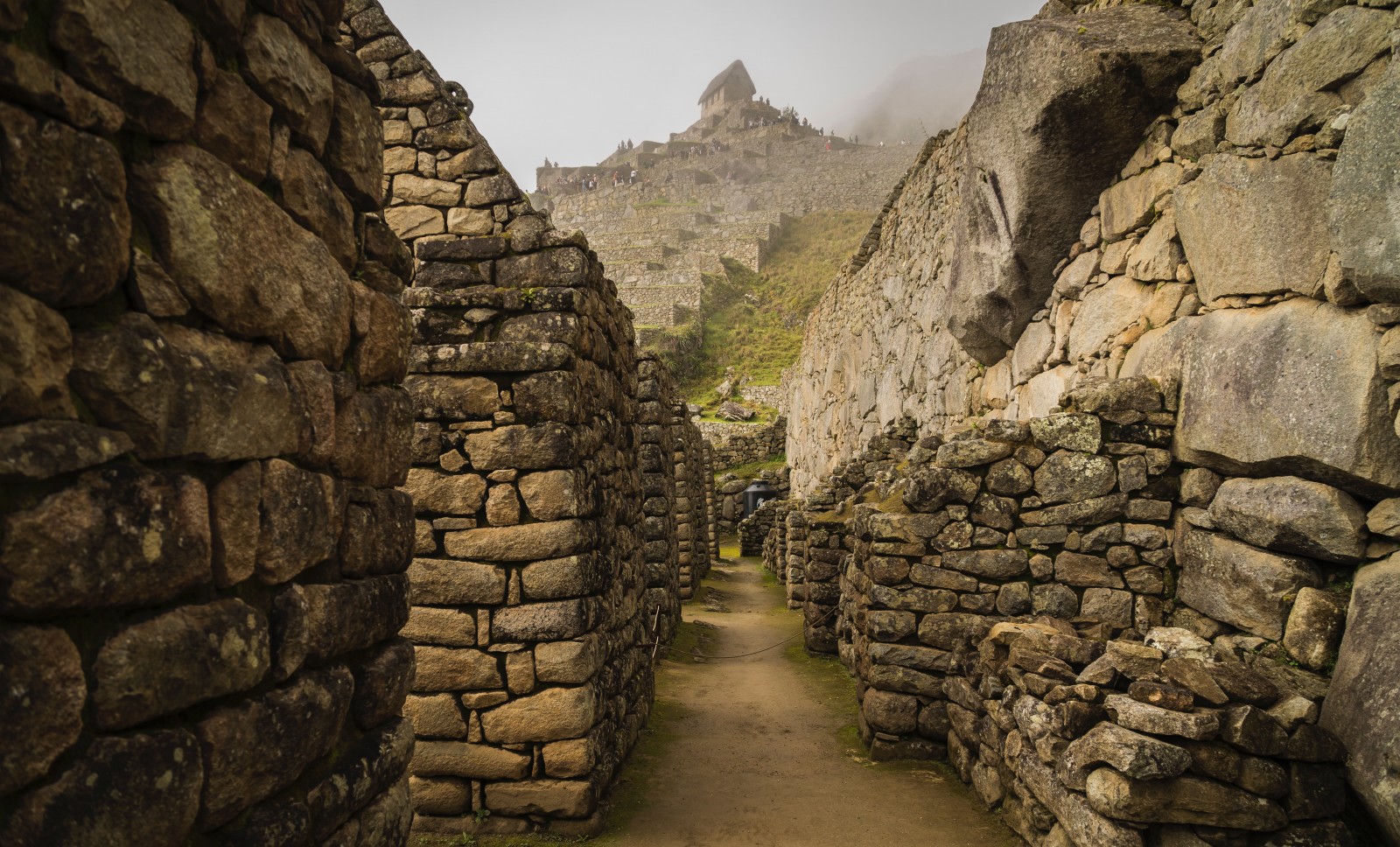 machu picchu peru stacked grey stone walkways with misty clouds and green shrubs