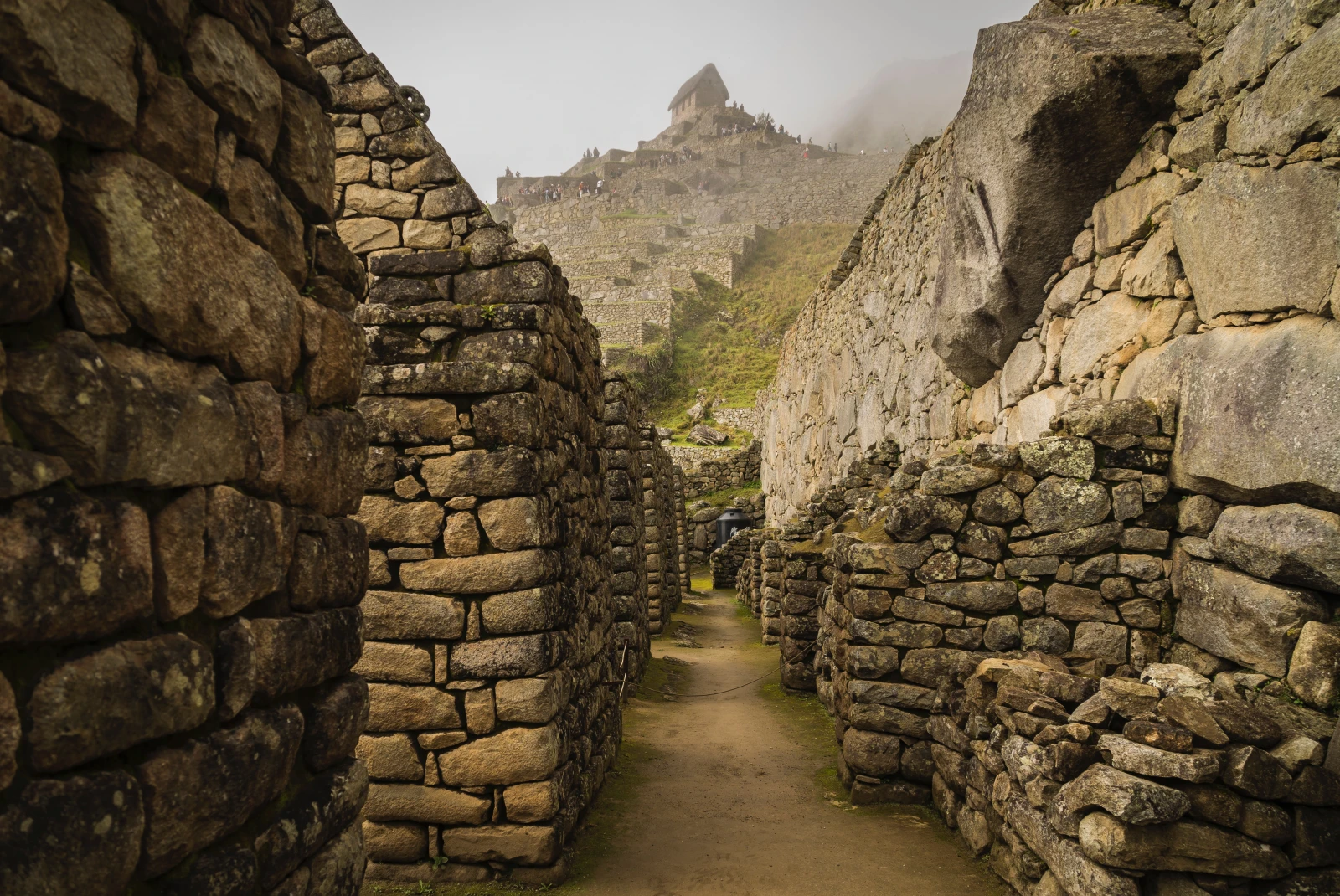 machu picchu peru stacked grey stone walkways with misty clouds and green shrubs