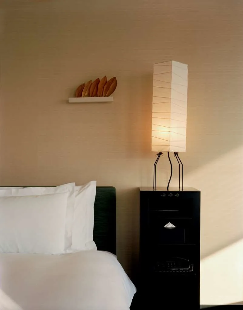 a close up of a lantern-like lamp on a black table near a bed 
