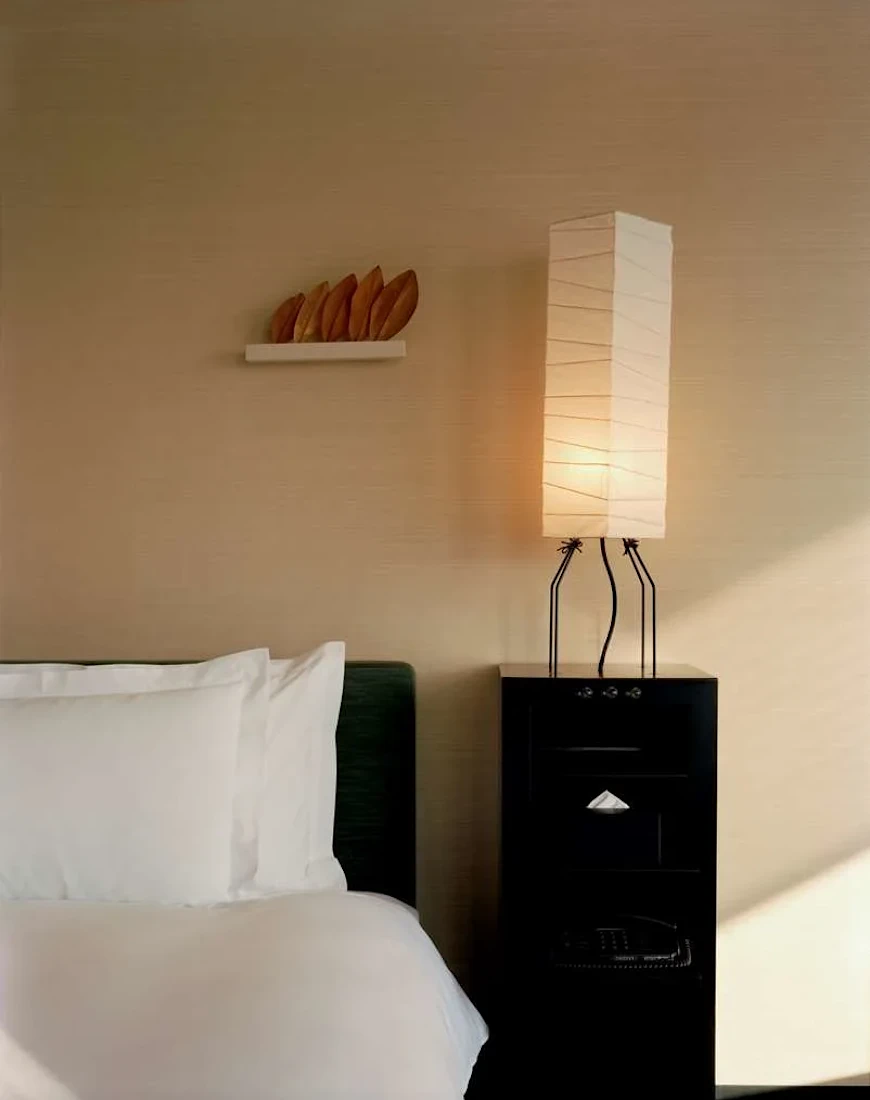 a close up of a lantern-like lamp on a black table near a bed