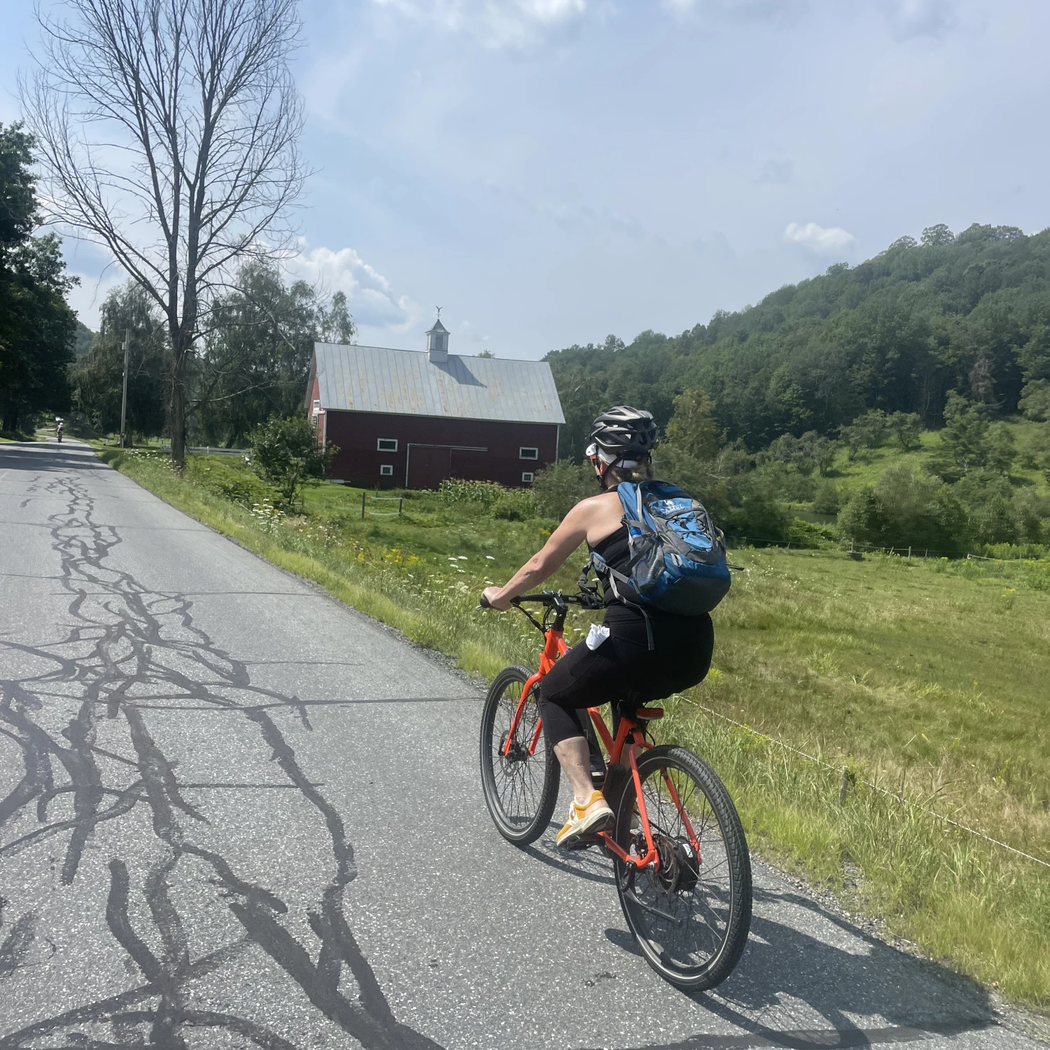Advisor Kim Richter biking on the road along  green grounds