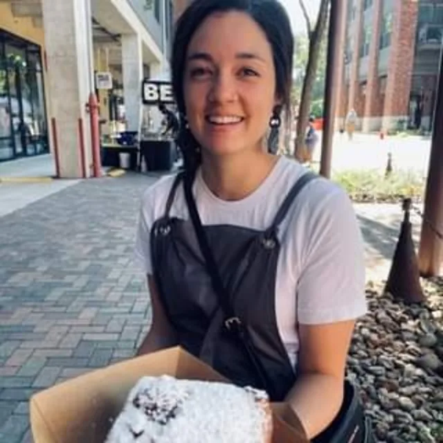 Travel Advisor Erin Riggs in a white t-shirt holding a pastry. 