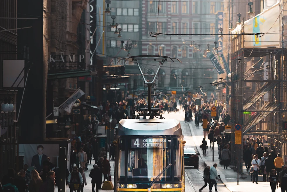 Downtown Helsinki street with a tram and people.