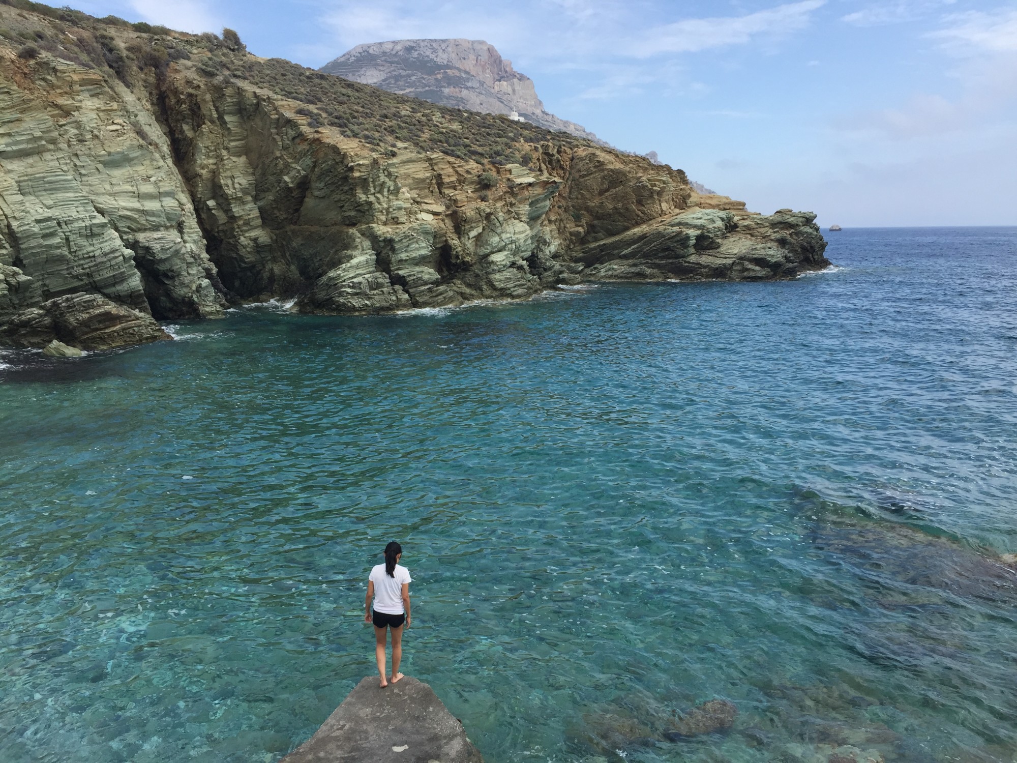 travel advisor stands on a rock over the beach