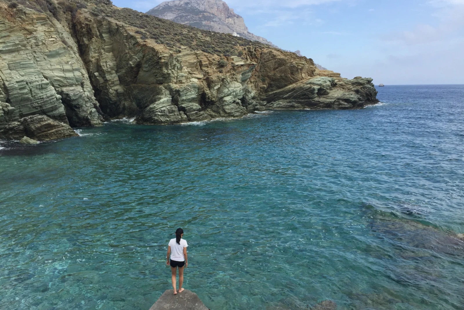 travel advisor stands on a rock over the beach