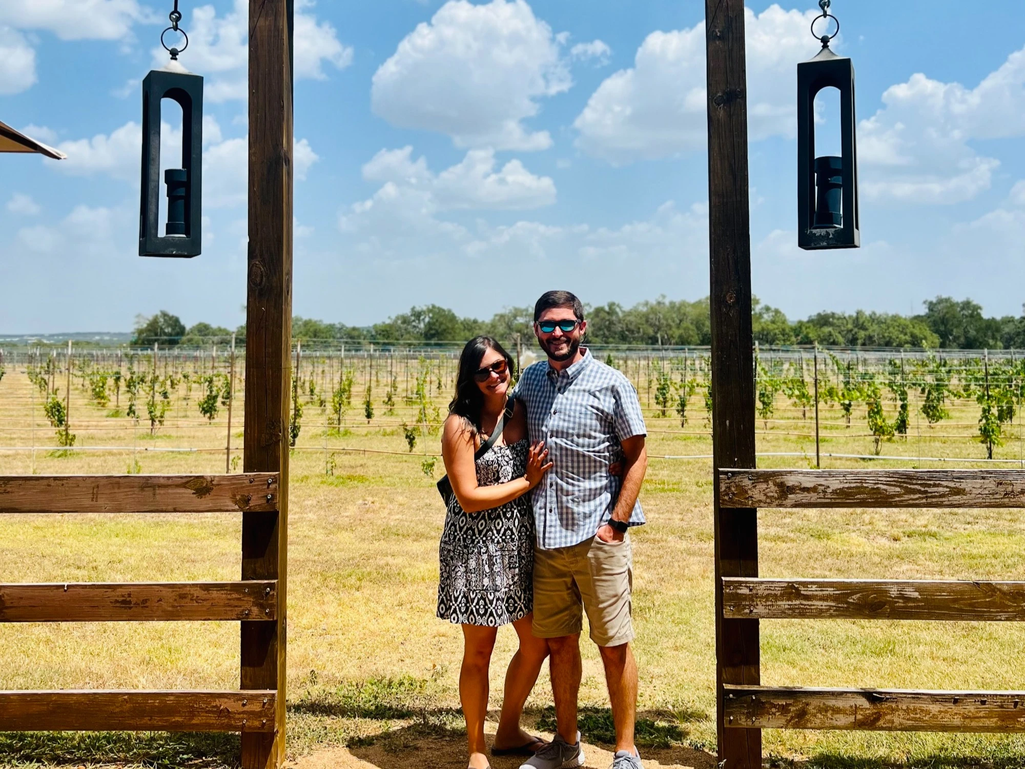 A man and woman standing in front of a vineyard.