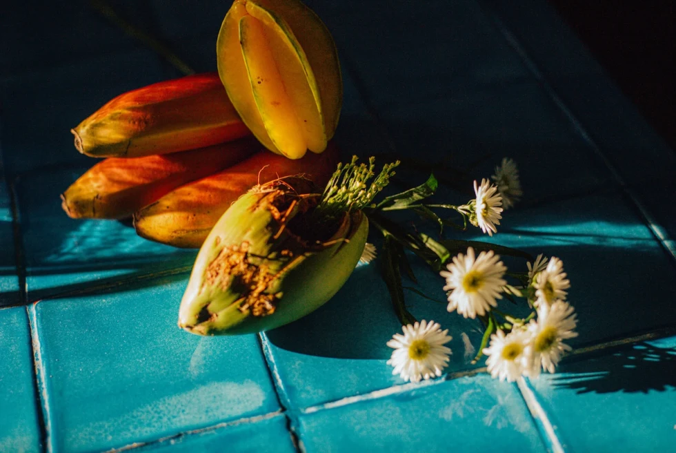 tropical fruits and daisies lying on a blue-tiled countertop