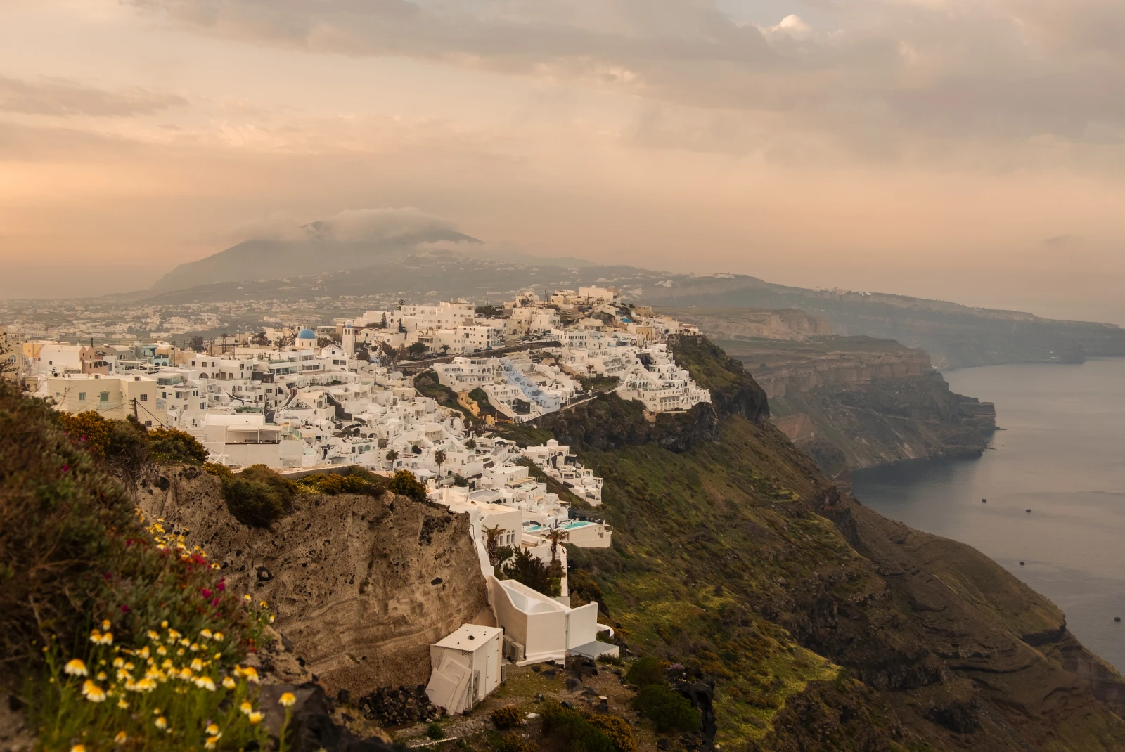 white buildings on the side of a cliff during sunset