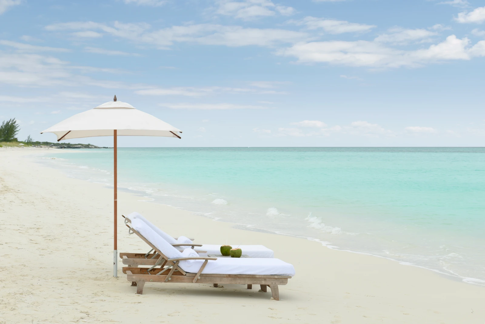 two lounge chairs on a white beach during daytime