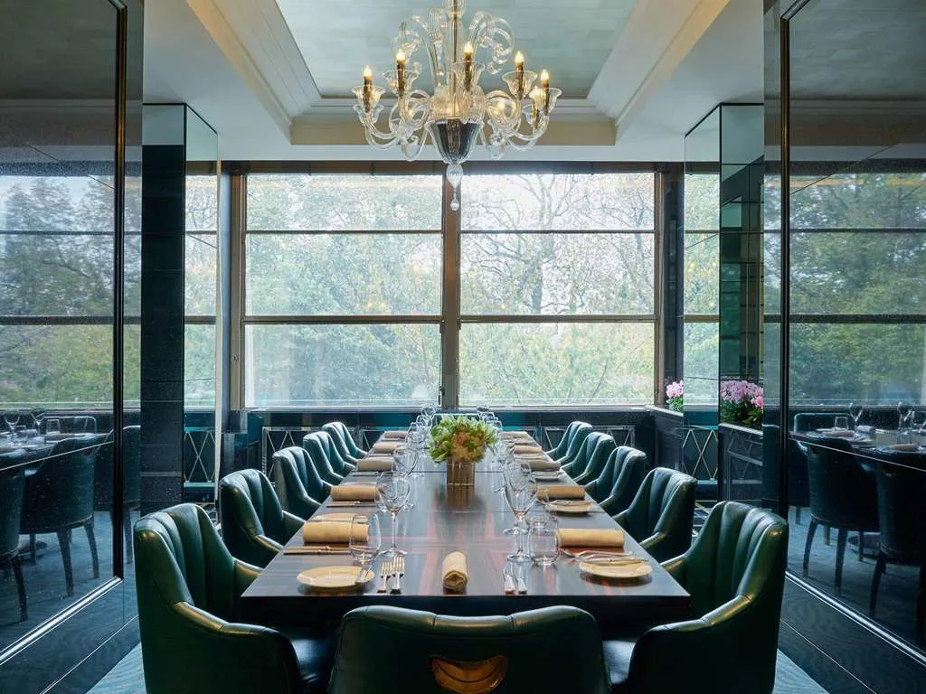 a long wooden table surrounded by fancy green leather chairs