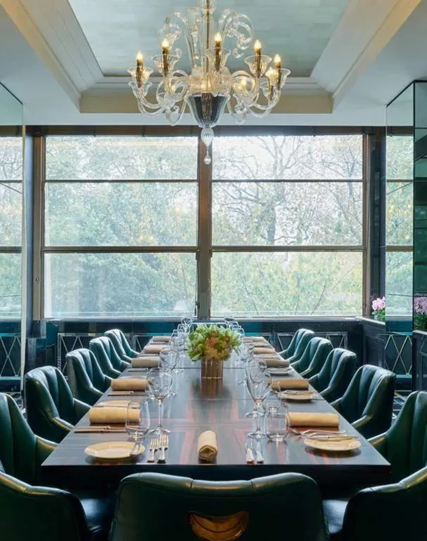 a long wooden table surrounded by fancy green leather chairs