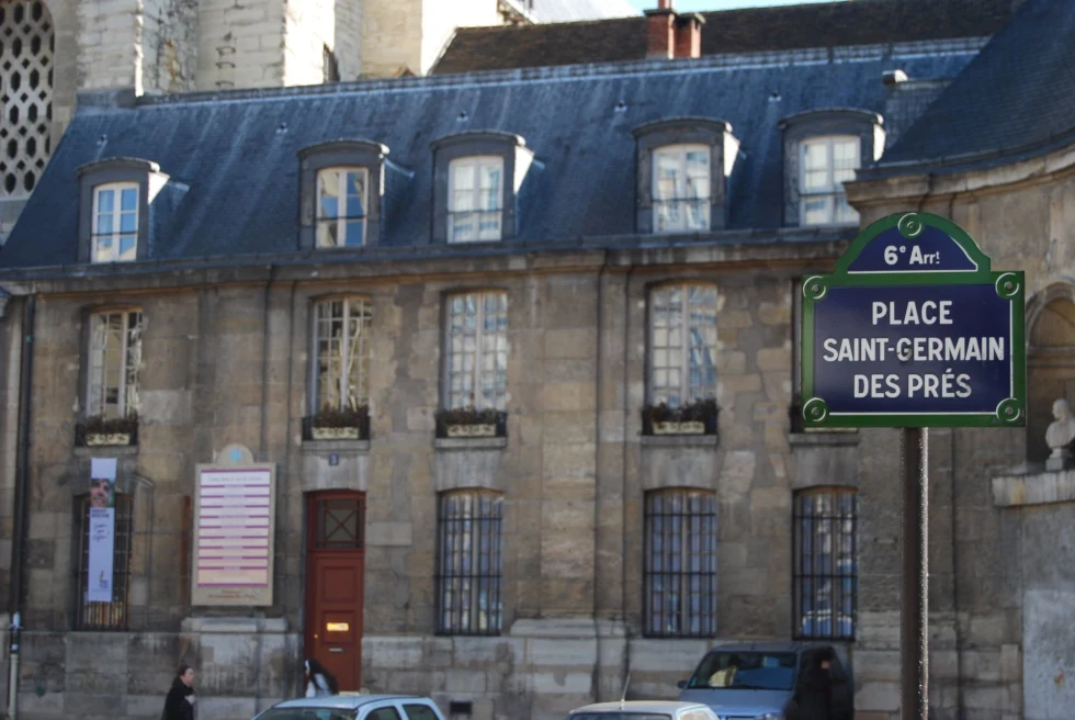 old stone building and a street sign that res, "place saint-germain des pres"