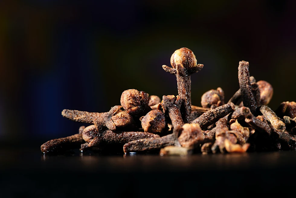a pile of brown clove spices on a black table