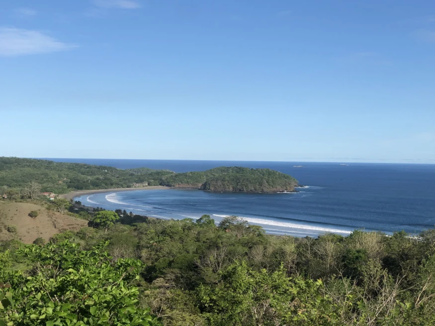 view from the top of hill of a beach cove with blue skies 