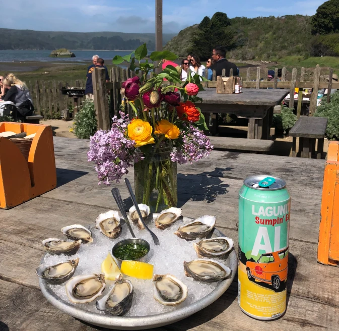 oysters, flowers and a canned drink on a wooden table