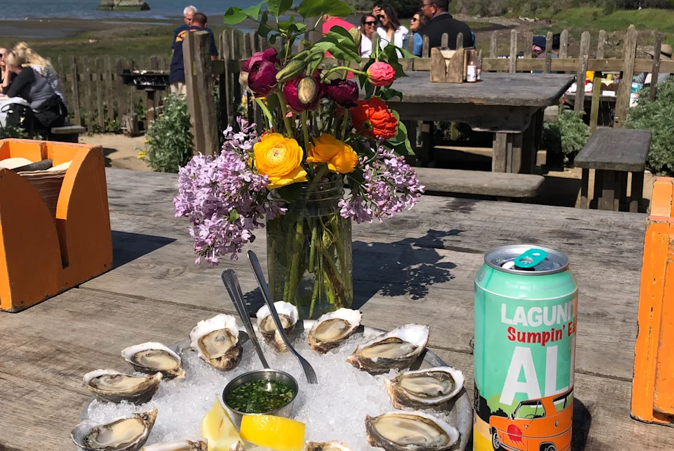 oysters, flowers and a canned drink on a wooden table