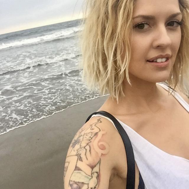 Selfie of a blond woman standing in front of the beach