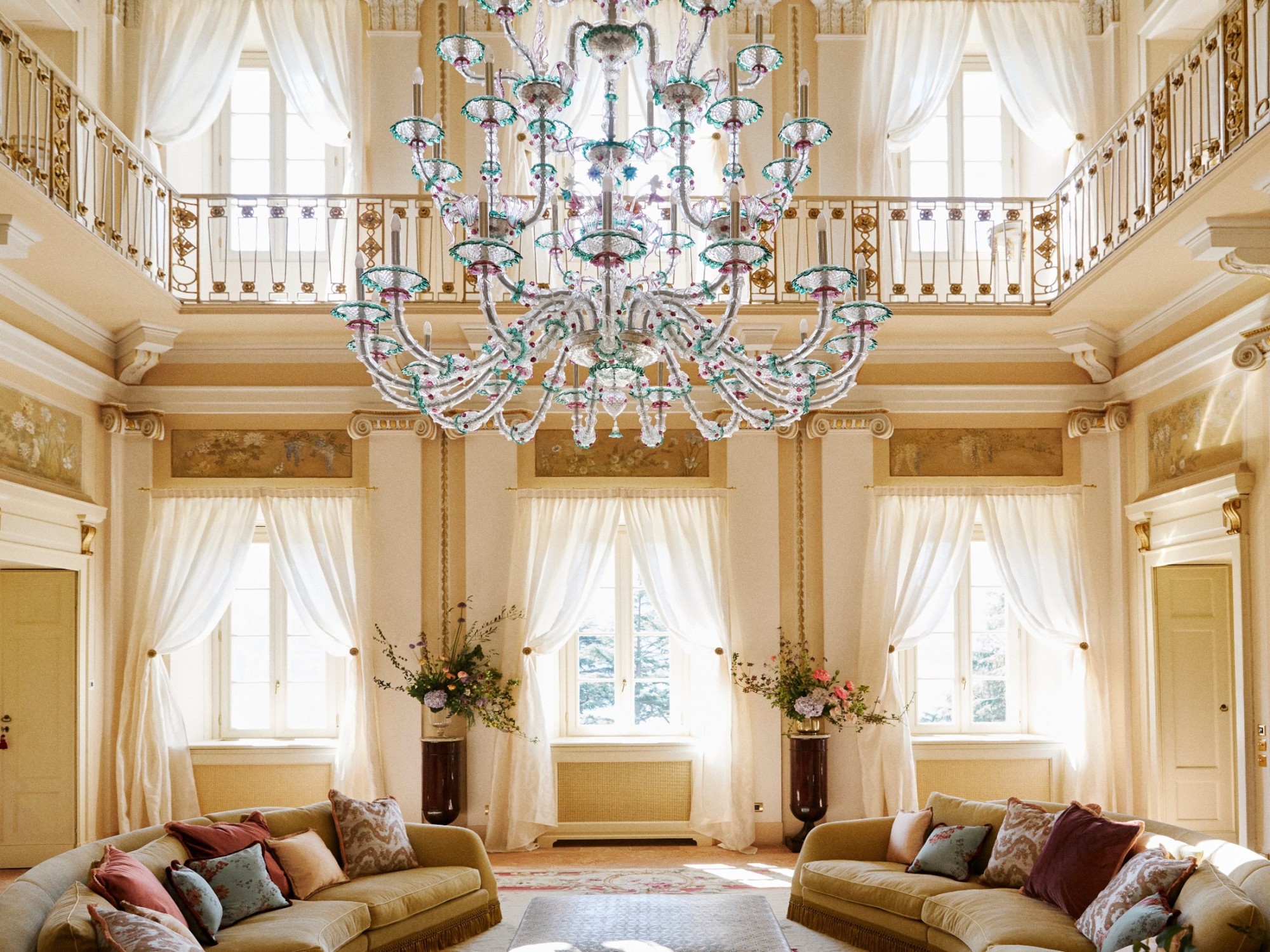 a large glass chandelier hands in an opulent light-filled room with cream-colored walla