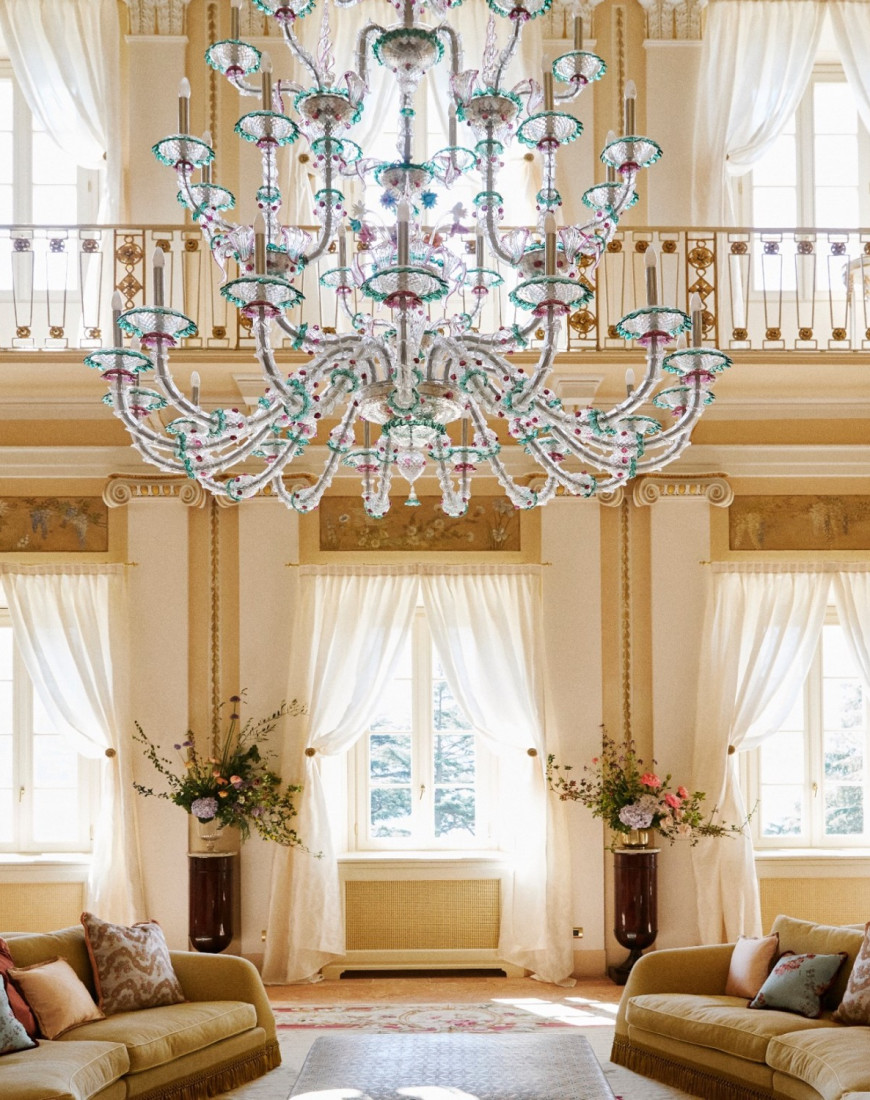 a large glass chandelier hands in an opulent light-filled room with cream-colored walla