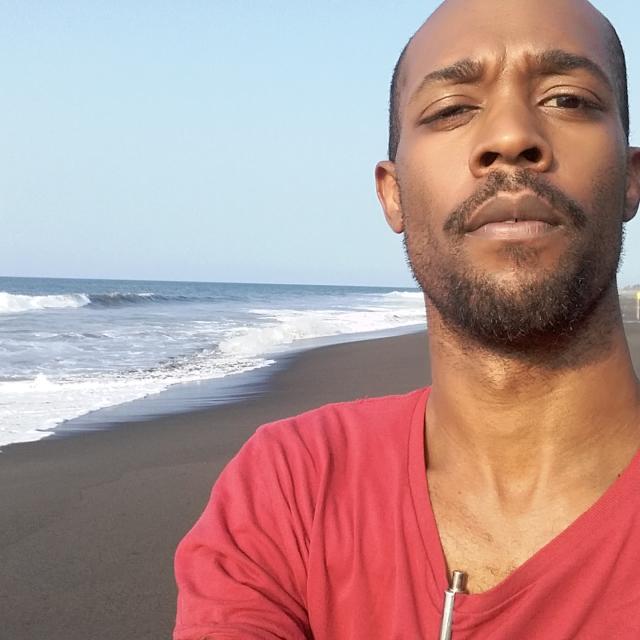 Fora travel agent Paul White wearing red shirt standing on beach