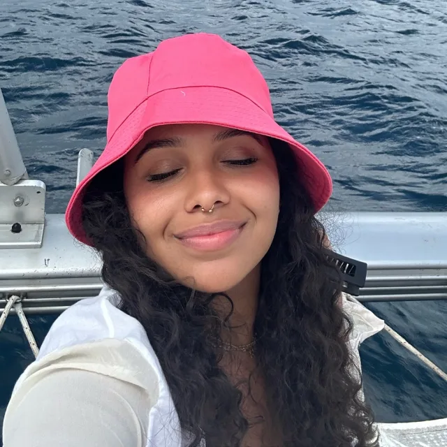 Travel advisor Hazel Peña poses on a boat wearing a pink bucket hat.