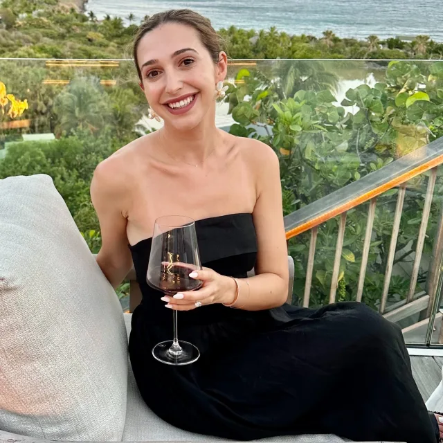 gabriella in a black dress sipping wine
