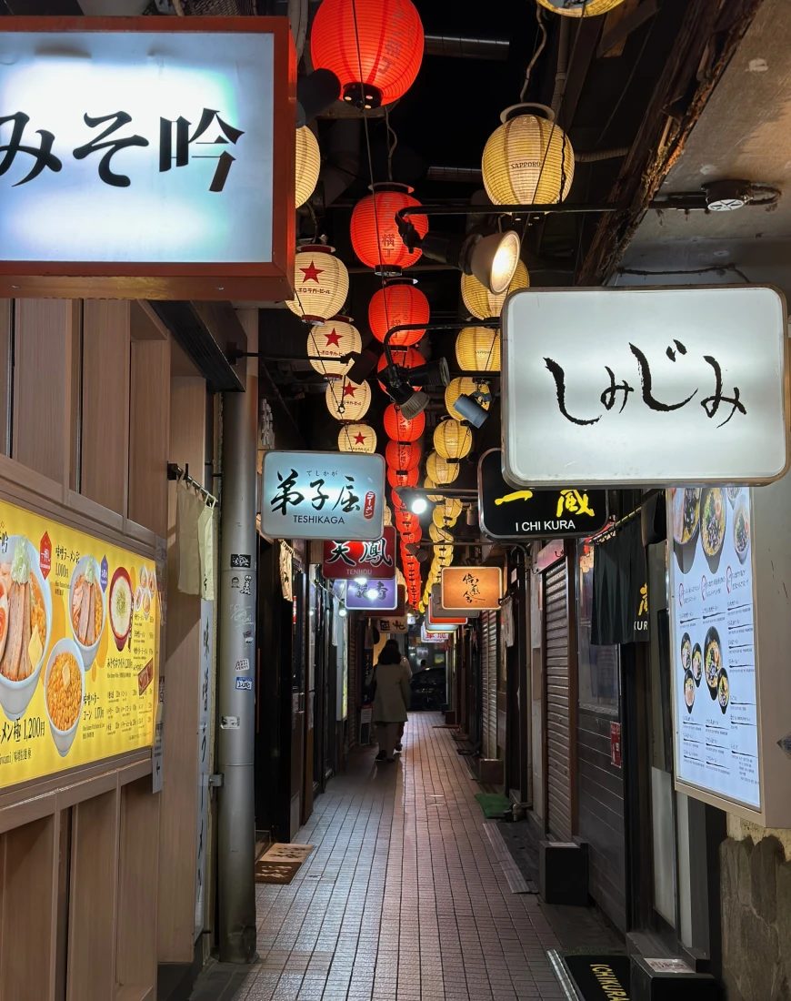 An alleyway with food stalls and lanterns overhead in Sapporo.