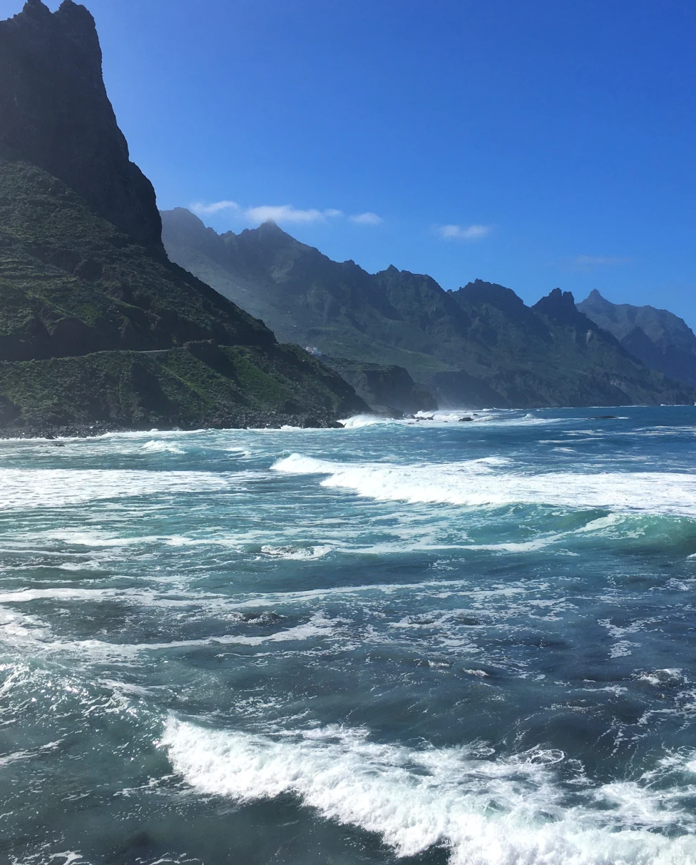 A sea with blue water and mountains at the back. 