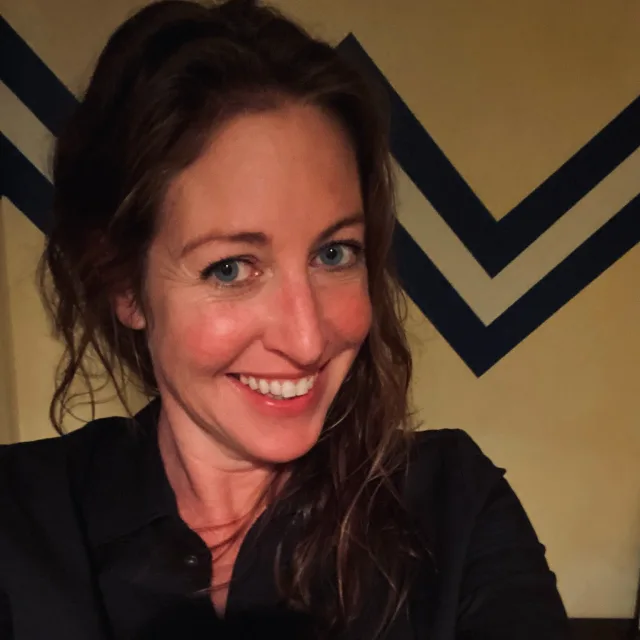 Travel Advisor Jessica Murphy in a black shirt in front of a yellow and blue wall.