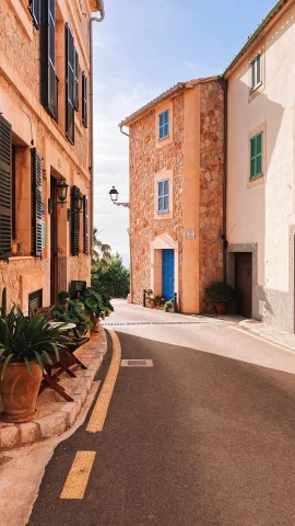Quiet street in Mallorca heading towards ocean on sunny day.