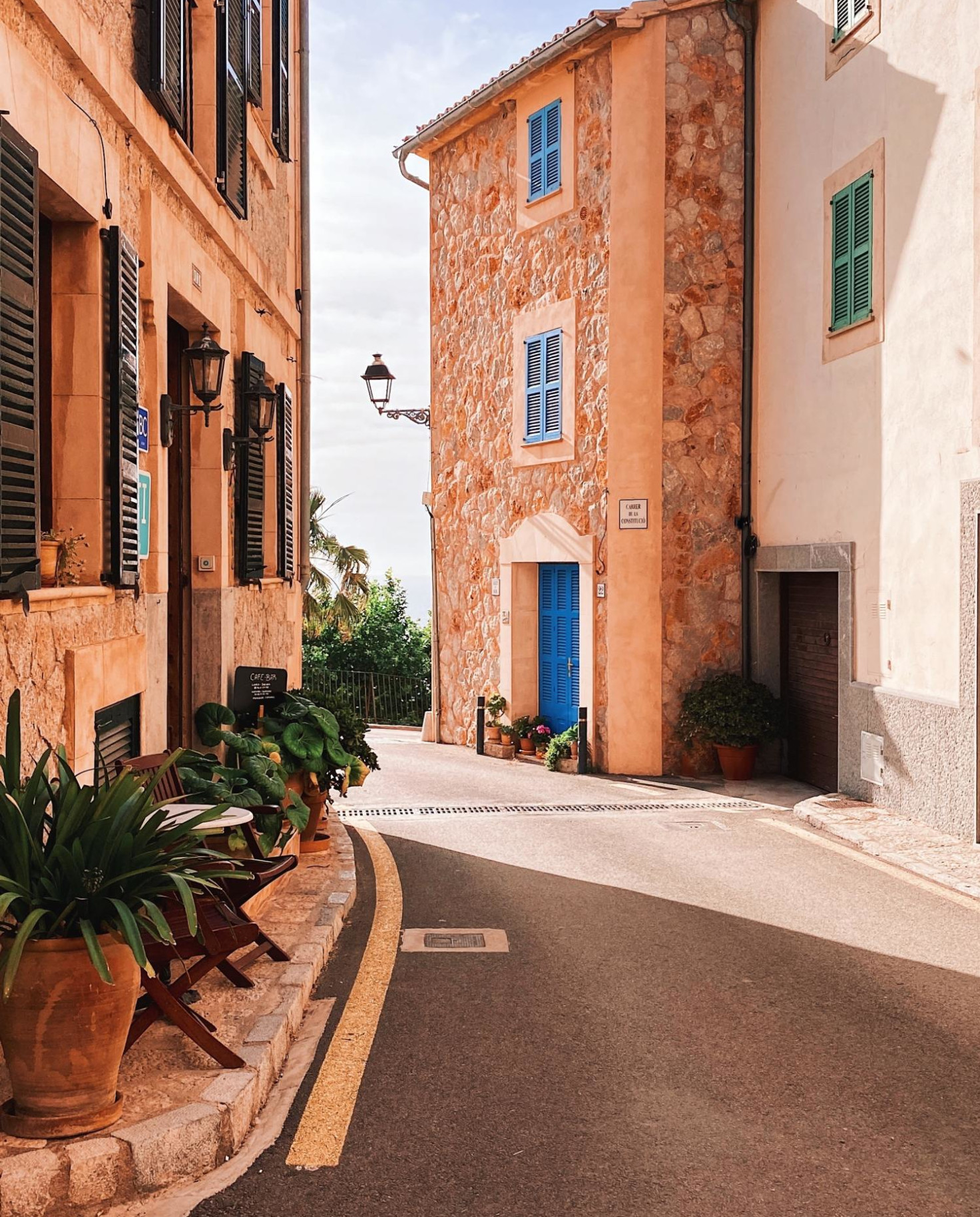 Quiet street in Mallorca heading towards ocean on sunny day.