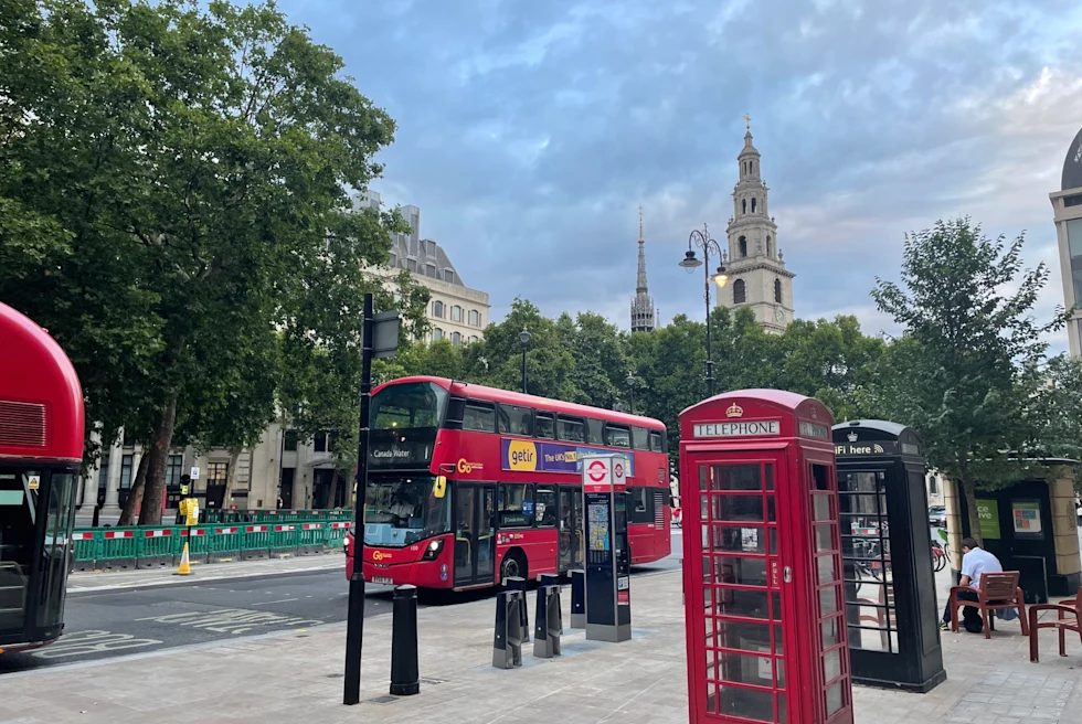 city street with double decker red bus and red phone booth during the day