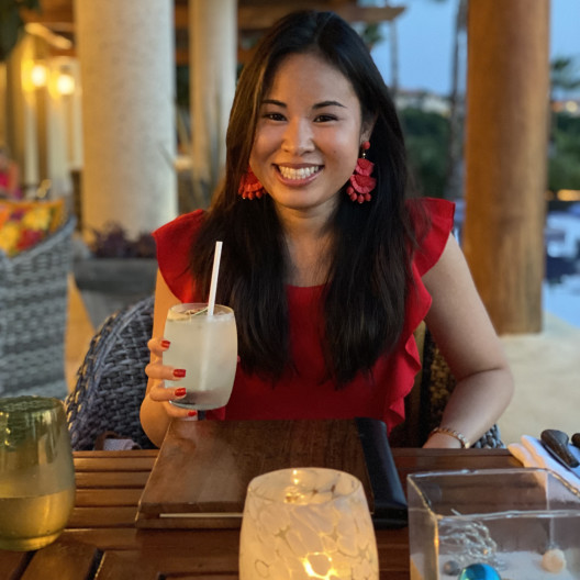 Fora travel agent Kristyne Wada wearing red dress and holding drink