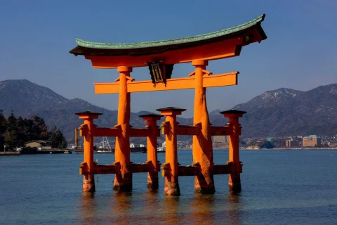 japan orange spiritual gate in water with mountains in the background