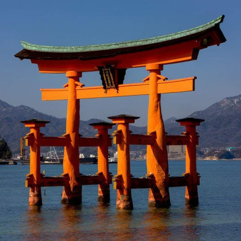 japan orange spiritual gate in water with mountains in the background