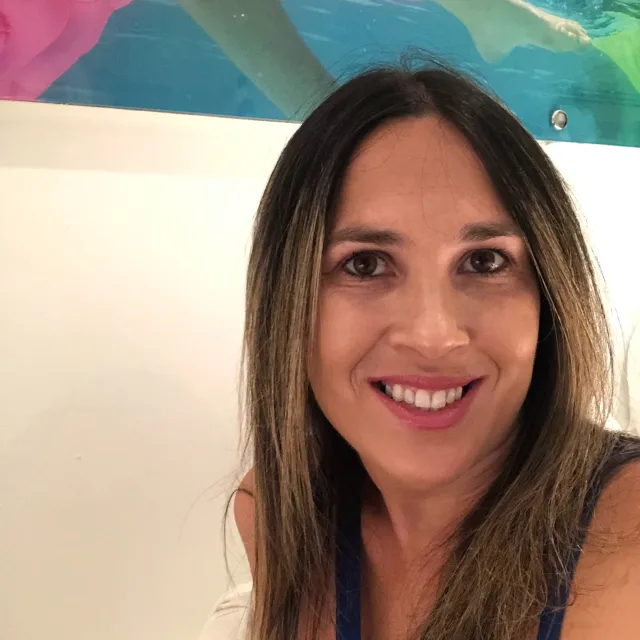 Travel Advisor Angela Allas in a black top with a colorful painting and white wall.