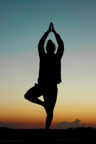 Silhouette of a person in a standing yoga pose during the sunrise