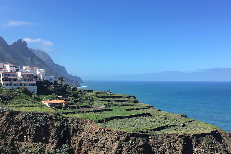 Sea with blue water, mountains and a building.